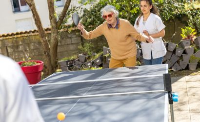 Résidente qui joue au Ping Pong à l'extérieur en compagnie d'une soignante.